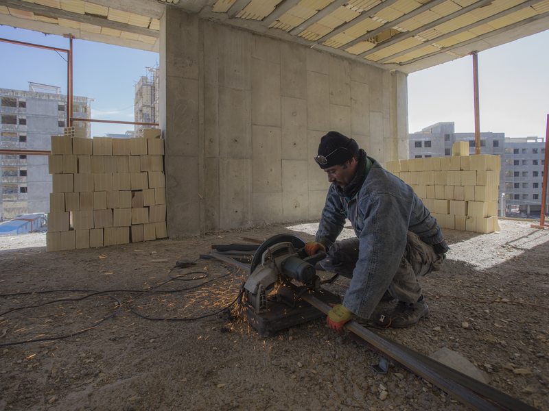 Bouwvakker werkt met een elektrisch gereedschap in een gebouw in aanbouw.
