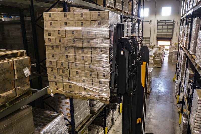 Pallets met goederen en een medewerker in een distributiemagazijn.