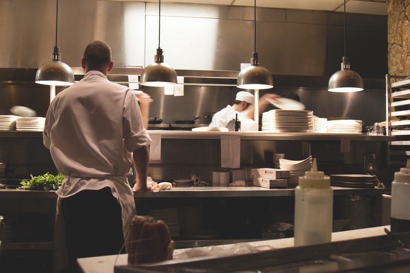 Koks bereiden gerechten aan de uitgifte in een professionele keuken.