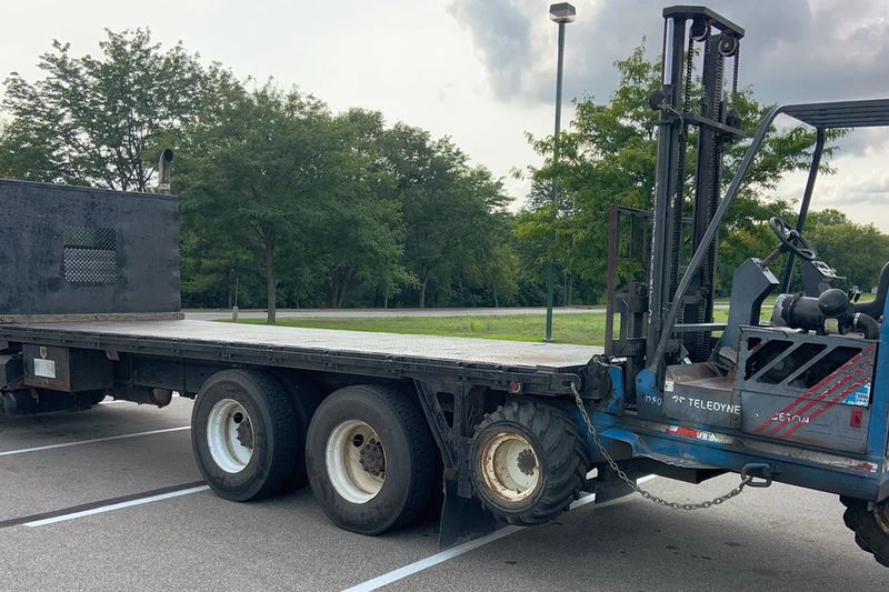 Een heftruck laadt goederen in een container bij een magazijn.