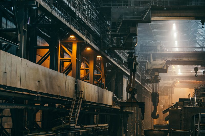 Machines, loopbruggen en werkplekken in een fabriekshal.