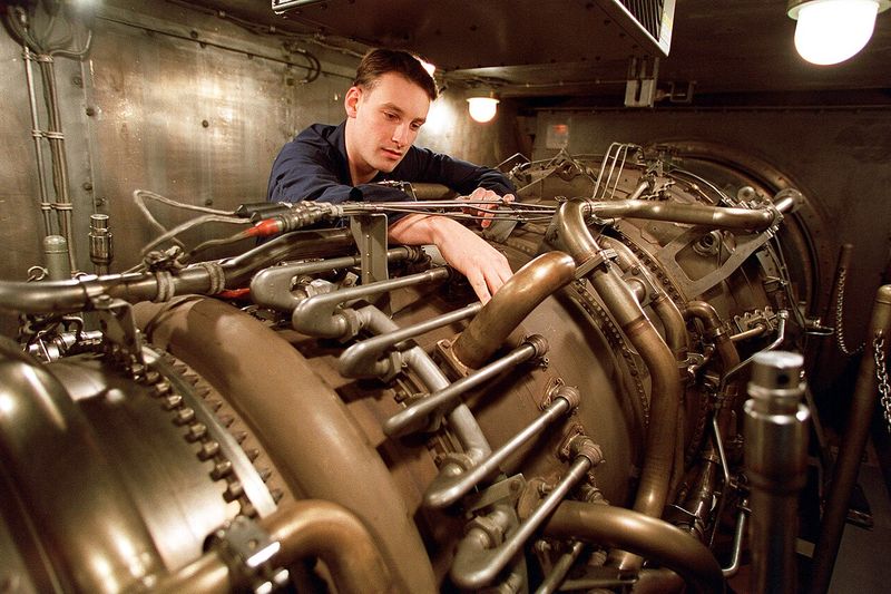 Monteur werkt aan een motor in een onderhoudswerkplaats.